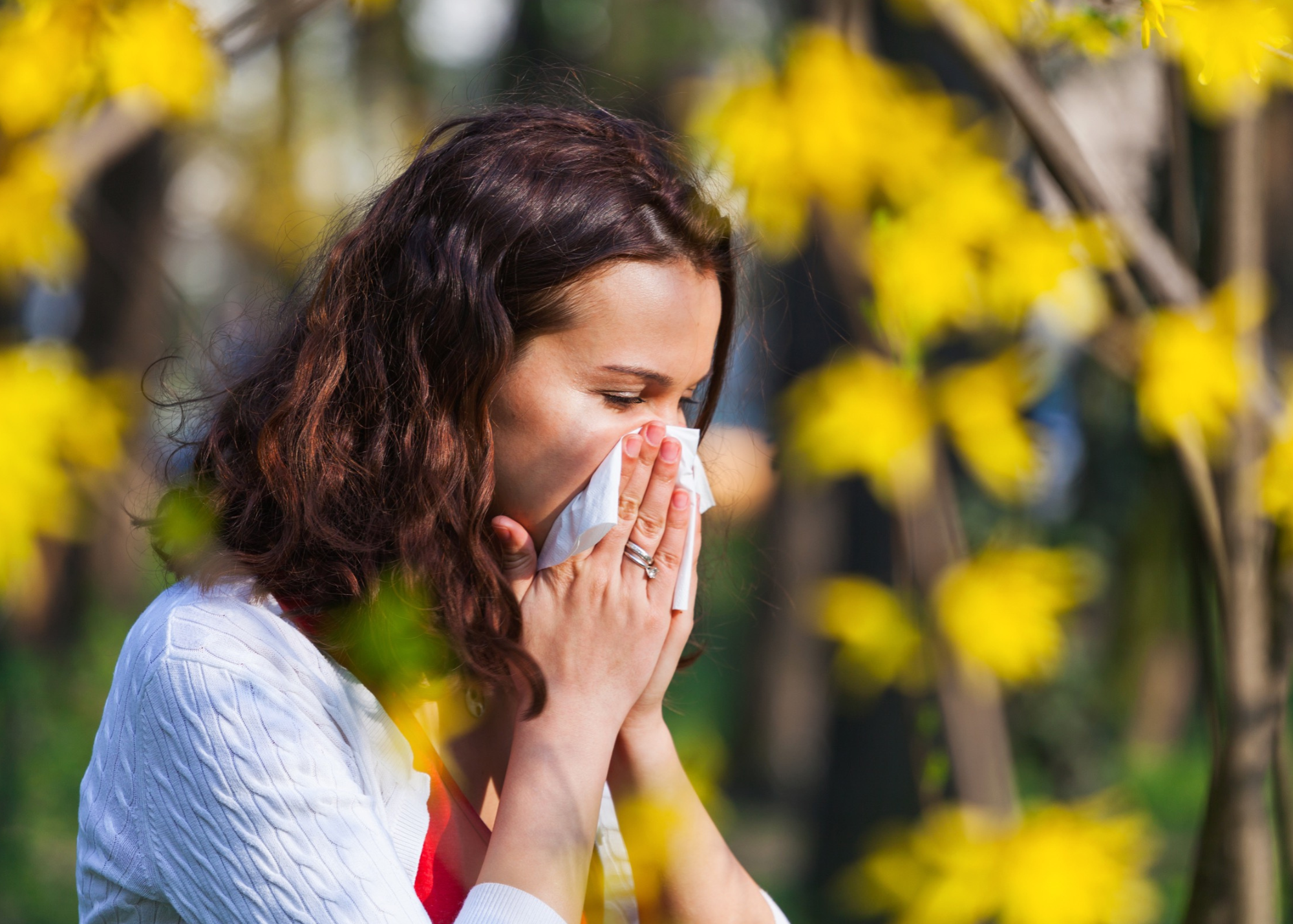 Person standing outdoors sneezing