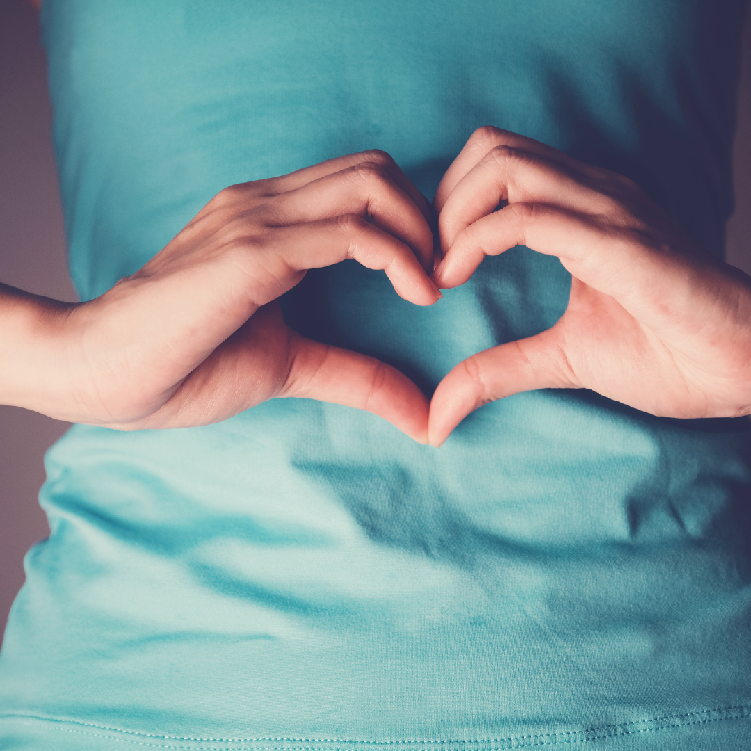 Person making a heart symbol over their digestive system