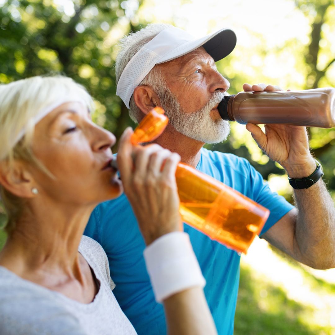 Two people drinking water out of water bottles