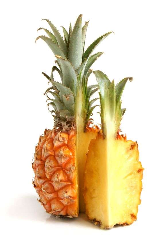 Ripe pineapple with bright yellow flesh, brown outer covering and green stalk