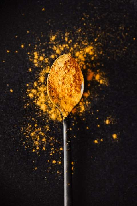Gold-colored Turmeric powder on a silver spoon