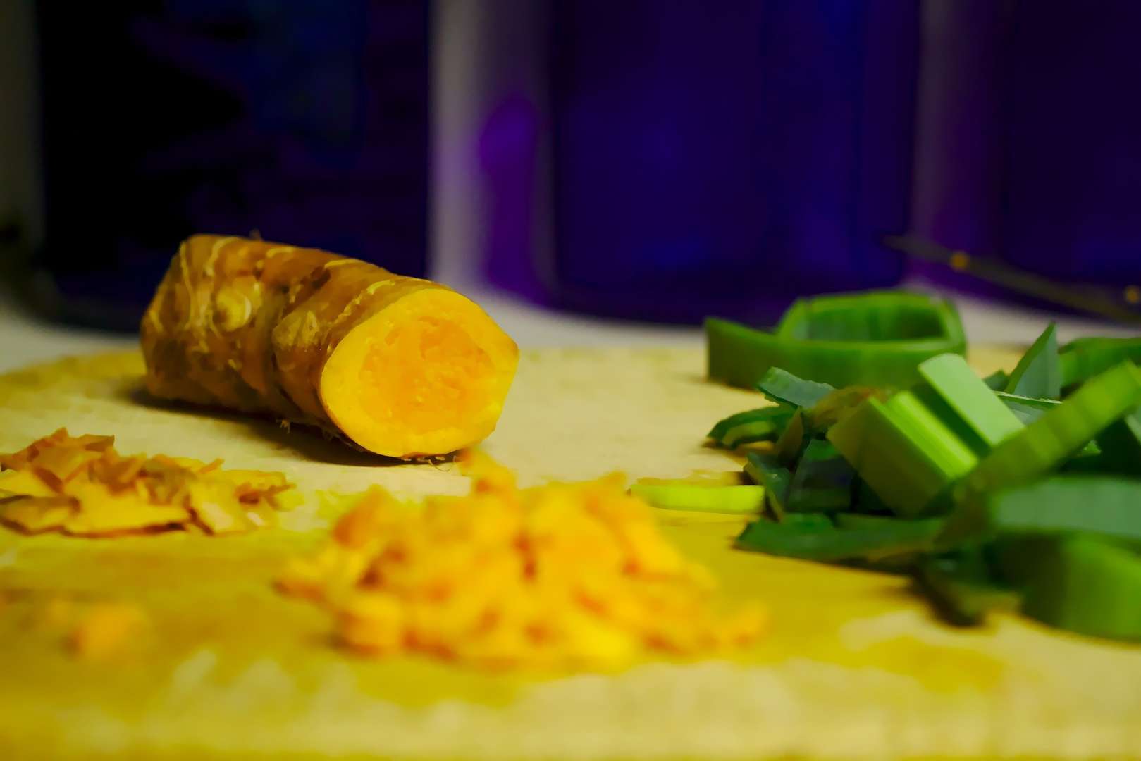 Bright orange pieces of chopped Turmeric next to turmeric root